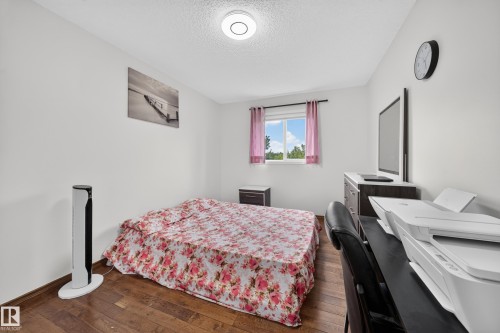 Room featuring wood-finish flooring, white walls, and a window with pink drapes - 4 4350 23 Street, Edmonton, AB 