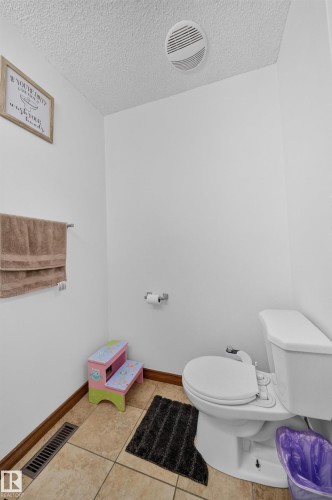 Bathroom featuring ceramic tile flooring, a white toilet, and a ceiling-mounted ventilation fan - 4 4350 23 Street, Edmonton, AB 
