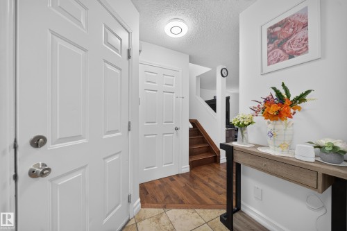 Entryway featuring a panel door, ceiling-mounted light fixture, and tile flooring transitioning to wood-finish flooring - 4 4350 23 Street, Edmonton, AB 