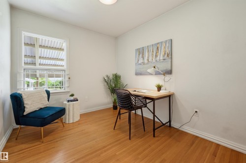 Light-filled room featuring wood-finish flooring, white baseboards, and a single window with exterior security bars - 11619 122 Street, Edmonton, AB 