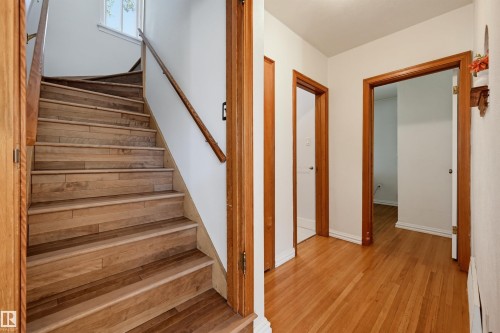 Hardwood staircase featuring a wood railing and white risers - 11619 122 Street, Edmonton, AB 