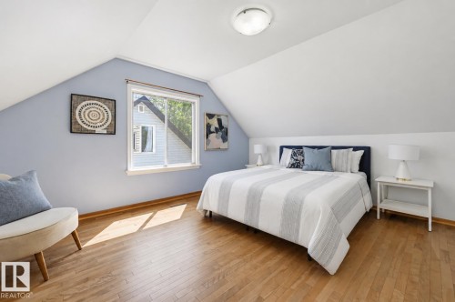 Room featuring sloped ceilings, hardwood flooring, and a large window with white trim - 11619 122 Street, Edmonton, AB 