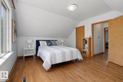 Wood-finish flooring throughout, complemented by sloped ceilings and a flush-mount ceiling light fixture - 