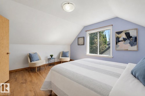 Angled ceiling room featuring wood-finish flooring, a double window, and a flush mount ceiling light fixture - 11619 122 Street, Edmonton, AB 