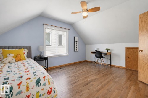 Attic bedroom featuring wood-finish flooring, a ceiling fan with light fixture, and a window with blinds - 11619 122 Street, Edmonton, AB 