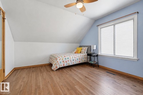 Room featuring wood-finish flooring, a ceiling fan, and sloped ceilings - 11619 122 Street, Edmonton, AB 