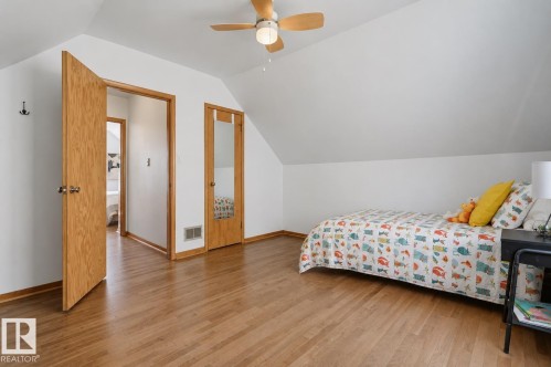 Bedroom featuring wood-finish flooring, a ceiling fan with integrated lighting, and a sloped ceiling - 11619 122 Street, Edmonton, AB 