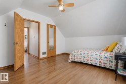 Bedroom featuring wood-finish flooring, a ceiling fan with integrated lighting, and a sloped ceiling - 
