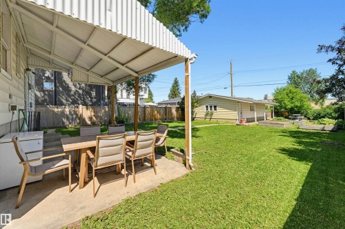 Expansive backyard featuring a covered patio with concrete flooring, a detached garage, and a manicured lawn - 11619 122 Street, Edmonton, AB 