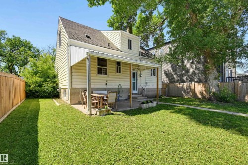 Expansive backyard featuring a covered patio, concrete slab, and wood privacy fencing - 11619 122 Street, Edmonton, AB 
