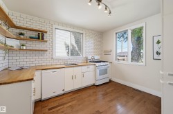 Kitchen featuring white subway tile backsplash, wood-finish countertops, white cabinetry, and wood-finish flooring - 