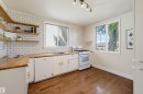 Kitchen featuring white subway tile backsplash, wood-finish countertops, white cabinetry, and wood-finish flooring - 11619 122 Street, Edmonton, AB 