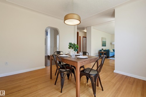 Dining area featuring wood-finish flooring, a contemporary ceiling light fixture, and arched doorways - 11619 122 Street, Edmonton, AB 