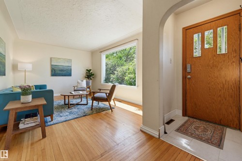 Entryway featuring a wood-panel door with decorative glass inserts, opening to an interior with light wood-finish flooring - 11619 122 Street, Edmonton, AB 