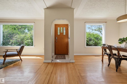 Entryway featuring an arched architectural detail, wood-finish flooring, and a paneled front door with decorative glass inserts - 11619 122 Street, Edmonton, AB 
