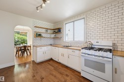 Kitchen featuring wood-finish flooring, white cabinetry, wood countertops, and a white subway tile backsplash - 