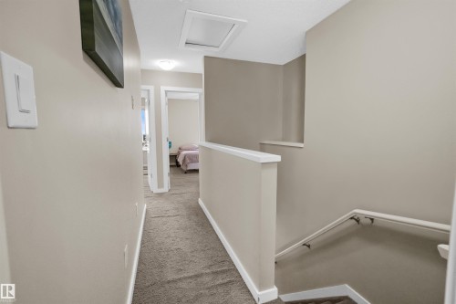 Upper-level hallway featuring neutral wall paint, carpeted flooring, and white trim - 13 2803 James Mowatt Trail, Edmonton, AB 