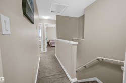 Upper-level hallway featuring neutral wall paint, carpeted flooring, and white trim - 