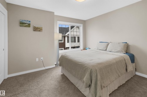 Carpeted room featuring a white window frame, light-colored walls, white baseboards, and a white interior door - 13 2803 James Mowatt Trail, Edmonton, AB 
