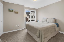 Carpeted room featuring a white window frame, light-colored walls, white baseboards, and a white interior door - 