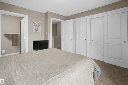 Carpeted bedroom featuring soft neutral wall tones, white trim, and multiple white panel doors - 13 2803 James Mowatt Trail, Edmonton, AB 