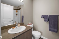 Bathroom featuring a wood-finish vanity with an integrated oval sink, speckled countertop, and chrome faucet - 