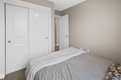 Bedroom featuring neutral paint, light-colored carpeting, white sliding closet doors, and a white paneled interior door - 