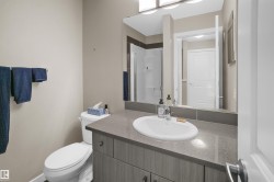 Bathroom featuring a single vanity with a white oval sink, a gray countertop, and wood-finish cabinetry - 