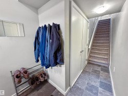 Entryway featuring durable slate-style tile flooring, a neutral wall color, and a built-in closet with double doors - 