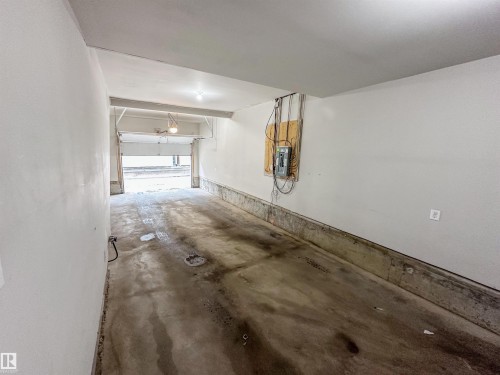 Spacious garage with a concrete floor, painted walls, overhead lighting, and an accessible electrical panel - 13 2803 James Mowatt Trail, Edmonton, AB 