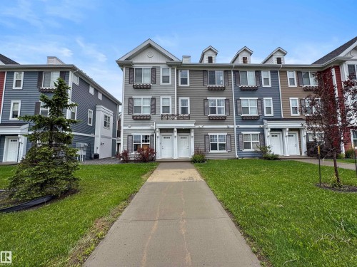 Contemporary townhome facade featuring multi-pane windows with decorative shutters and window boxes - 13 2803 James Mowatt Trail, Edmonton, AB 