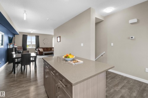 Kitchen island with a light-toned countertop and wood-finish cabinetry - 13 2803 James Mowatt Trail, Edmonton, AB 