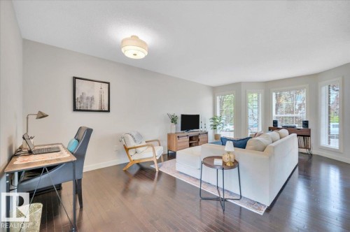 Spacious living area featuring rich wood-finish flooring and light-toned walls - 4865 Terwillegar Common, Edmonton, AB - Indoor Photo Showing Living Room