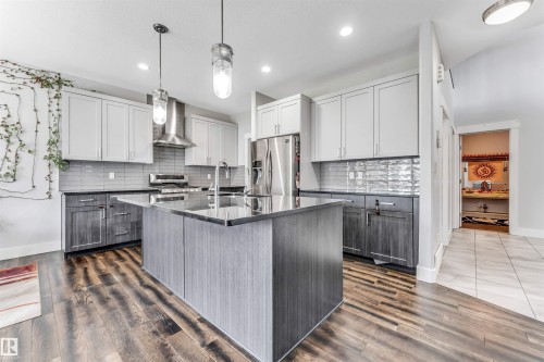 Contemporary kitchen featuring a central island, stainless steel appliances, dark wood-finish flooring, and two-tone cabinetry - 8516 216 Street, Edmonton, AB 