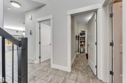 Hallway featuring light gray walls and patterned tile flooring - 