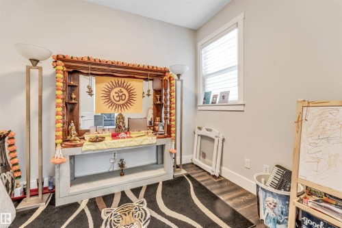 Neutral-toned room featuring wood-finish flooring and a single window with horizontal blinds - 8516 216 Street, Edmonton, AB 