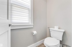 Compact bathroom featuring light gray walls, a white toilet, and a window with horizontal blinds - 