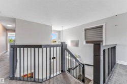 Upper-level landing featuring durable carpet flooring, a contemporary iron railing, and a window with blinds - 