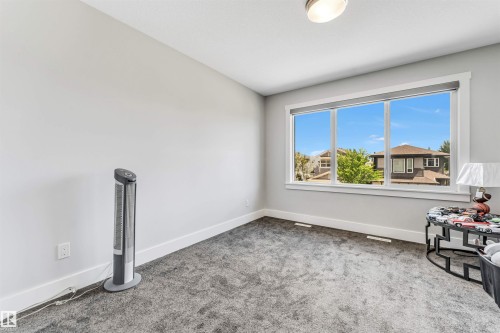 Bright room featuring light gray walls, plush gray carpeting, white baseboards, and a wide window with white trim - 8516 216 Street, Edmonton, AB 