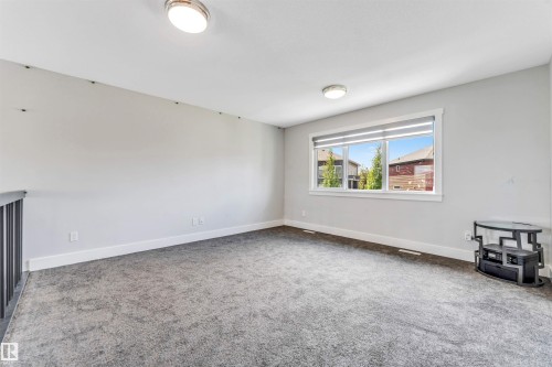 Spacious open-concept room featuring neutral gray walls and gray carpeting - 8516 216 Street, Edmonton, AB 
