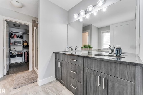 Bathroom featuring a double vanity with stone countertops, integrated sinks, and wood-finish cabinetry - 8516 216 Street, Edmonton, AB 