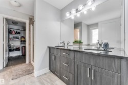 Bathroom featuring a double vanity with stone countertops, integrated sinks, and wood-finish cabinetry - 