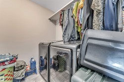 Laundry area featuring light-toned walls and wood-finish flooring - 