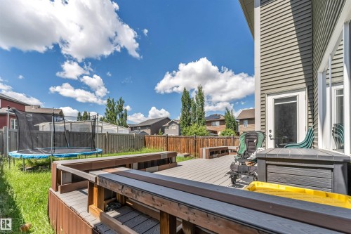 Spacious backyard featuring a multi-level composite deck with integrated bench seating, private wood fencing, and a manicured lawn area - 8516 216 Street, Edmonton, AB 