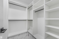 Custom closet system featuring white shelving, black hanging rods, and marble-look tile flooring - 