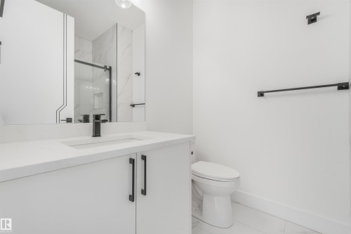 Modern bathroom featuring a white vanity with integrated sink, matte black hardware, and an expansive mirror - 1180 Genesis Lake Boulevard, Stony Plain, AB 