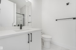 Modern bathroom featuring a white vanity with integrated sink, matte black hardware, and an expansive mirror - 