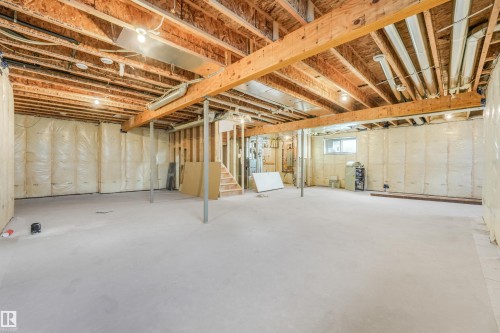 Unfinished basement featuring a concrete floor, exposed wood joists and beams, insulation-backed walls, and a visible window - 1180 Genesis Lake Boulevard, Stony Plain, AB 