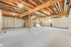 Unfinished basement featuring a concrete floor, exposed wood joists and beams, insulation-backed walls, and a visible window - 