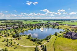 Expansive lakefront setting featuring a central lake, surrounding residential properties, extensive green spaces, and paved walking paths - 